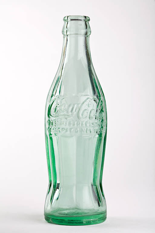 La Contour Bottle di Coca-Cola in vetro verde, studio d'oggetto su fondo neutro